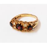 A hallmarked 9/375 gold ring, set with three garnets interspersed with two pairs of tiny opals