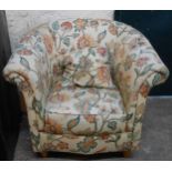 A modern tub armchair with floral print upholstery, set on polished wood turned front legs