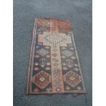 A Middle Eastern wool rug with central medallion and geometric guls - faded - size available on