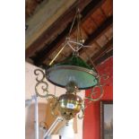 A brass hanging oil lamp with scroll supports and green glass shade