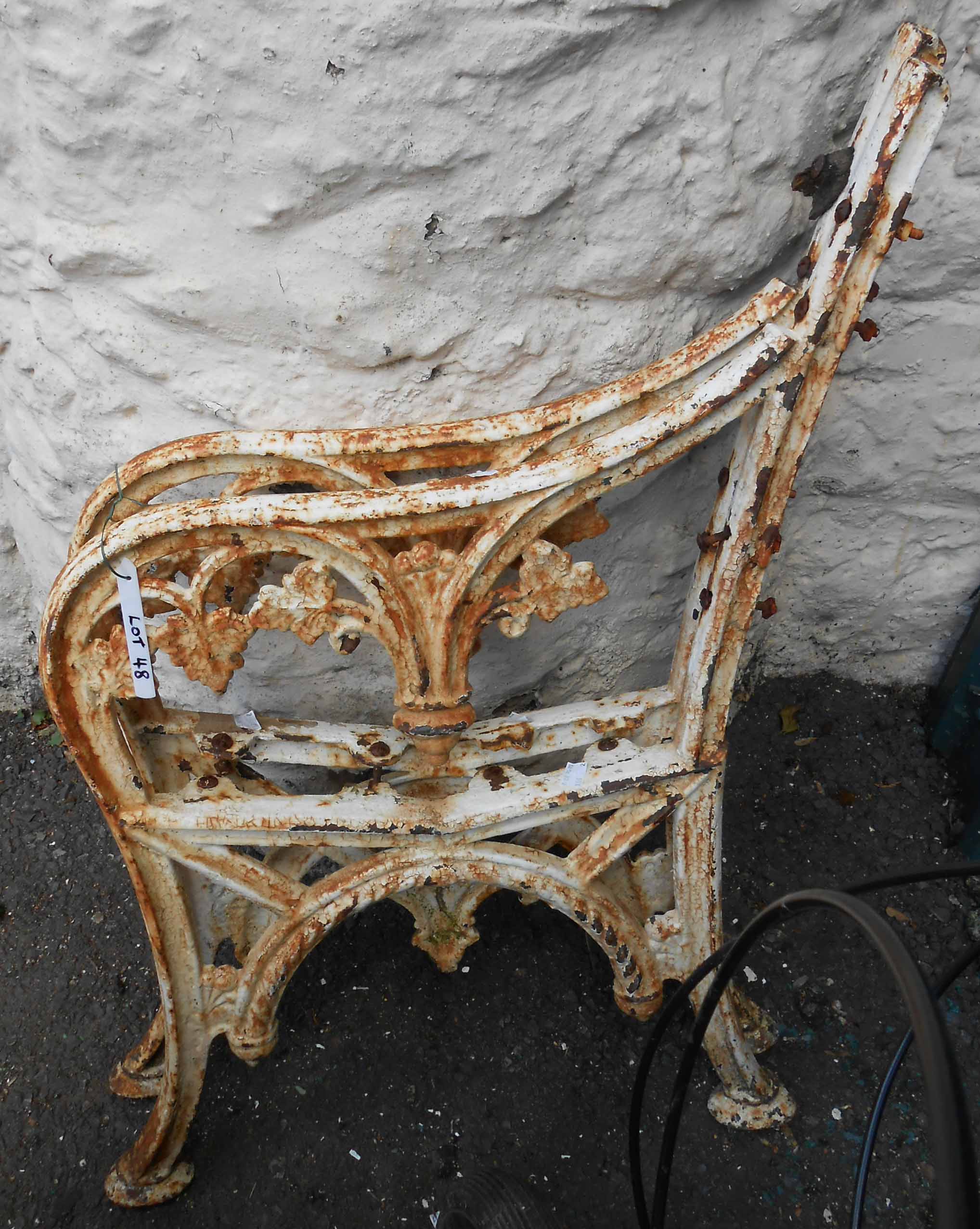 A pair of old painted cast iron bench ends with vine leaf decoration