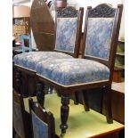 A set of four Victorian stained oak framed panel back dining chairs with decorative carved top rails