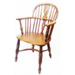 An antique Windsor elbow chair with solid elm moulded seat, set on ring turned supports