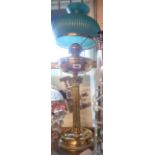 A brass table oil lamp with corinthian column, chimney, and reeded green glass shade