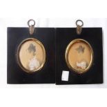 A pair of 19th Century black papier-mache and gilt metal mounted framed oval portrait miniatures,