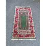 A Middle Eastern wool prayer mat featuring central mihrab and Mosque lamp within a floral border -