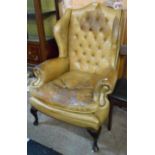 A 20th Century Georgian style wing back armchair with remains of studded leather upholstery, set