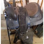 A modern Western saddle with stirrups and girth, on stand