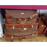 A graduated set of three vintage leather suitcases with canvas weather covers and locks marked for