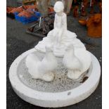 A white painted concrete birdbath with seated putto and two fan tailed pigeons - head cracked