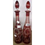 A pair of old Bohemian ruby flash cut glass decanters decorated with castles, stags, birds, and