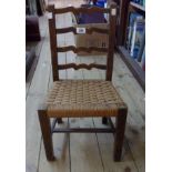 A stained wood framed child's ladder back chair with woven seagrass seat