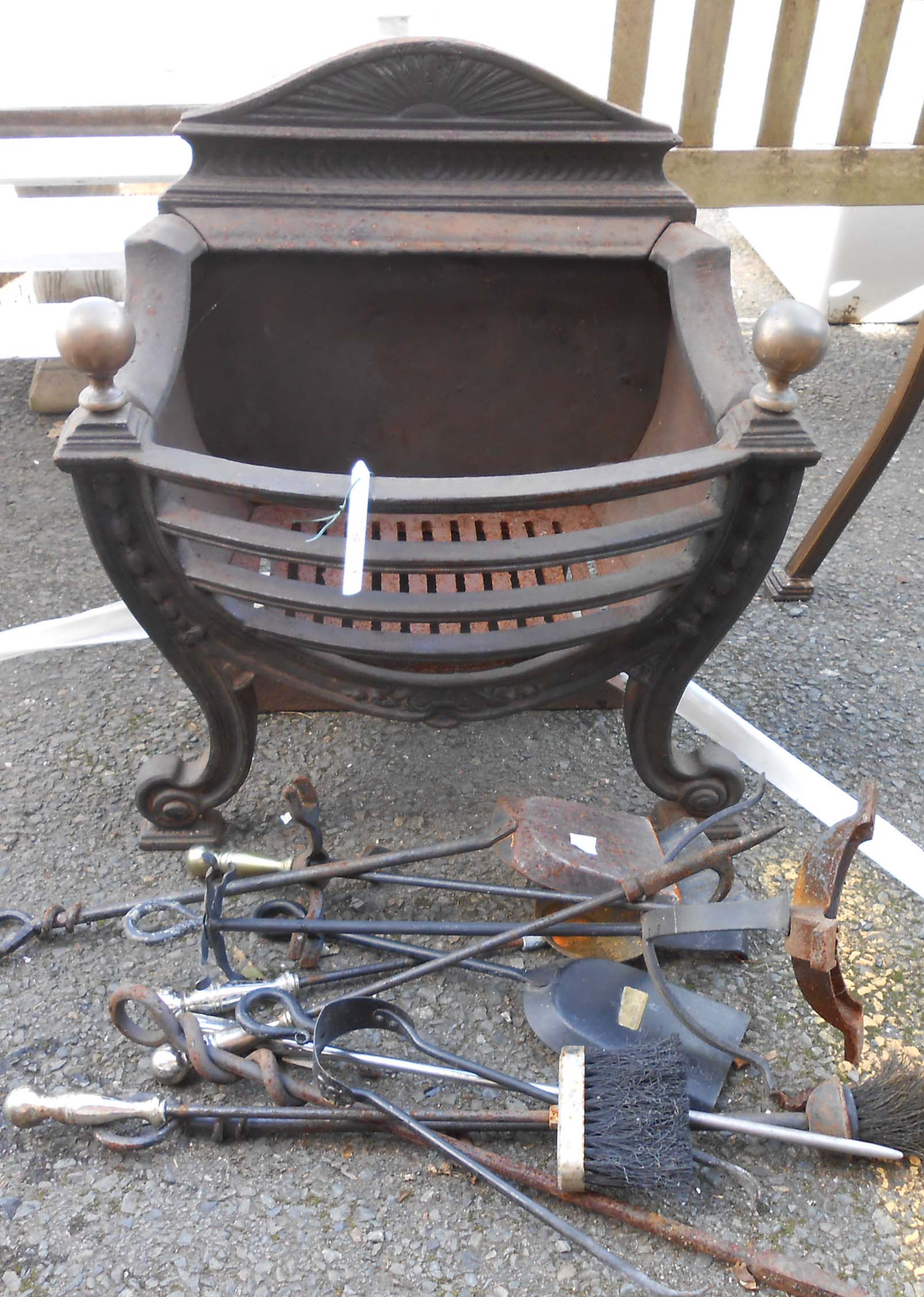 A large cast iron fire grate with brass finials, and various fire tools