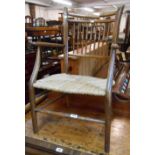 An antique stained wood framed stick back elbow chair with woven seagrass seat and turned front