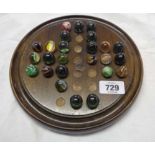 A old solitaire board with an incomplete set of antique and later marbles