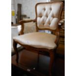 A reproduction stained wood framed elbow chair with studded button back upholstery, set on