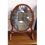 A 20th Century reproduction mahogany and strung oval dressing table mirror, set on slender swept