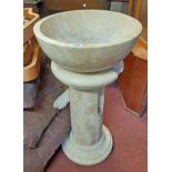 A 44.5cm diameter polished travertine sandstone basin, set on a column pedestal base with cut