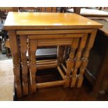 A nest of three stained wood tea tables, set on turned supports - sold with a modern polished wood