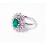 A marked 750 white metal ring, set with central oval emerald within a diamond encrusted starburst