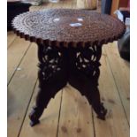 A 38cm diameter Indian carved hardwood and brass inlaid tea table, set on decorative folding