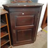 A 77cm antique oak wall hanging corner cupboard with canted sides and scalloped shelves enclosed