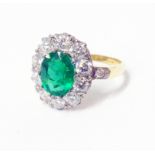 A high carat yellow metal ring, set with central oval 1.9ct emerald within a ten stone diamond