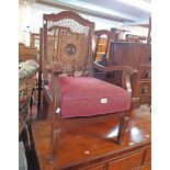 A 1930's decorative cane back elbow chair with central oak boss and original upholstered cushion,