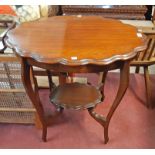 A 76cm early 20th Century stained mixed wood two tier occasional table with scalloped edge surfaces,