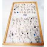 A wooden tray containing a collection of silver, 925, white metal and other charms and small