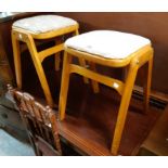 A pair of vintage stained wood kitchen stools with later upholstered seats, set on splayed legs