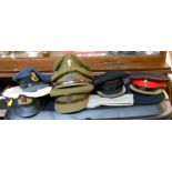 A collection of Post War military peaked caps, a beret, and a field service cap