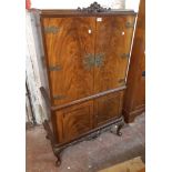 A 85cm vintage flame mahogany veneered drinks cabinet with ornate brass embellishments and strap