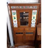 A 90cm early 20th Century walnut cabinet with central mirror panel door, later applied tiling, two