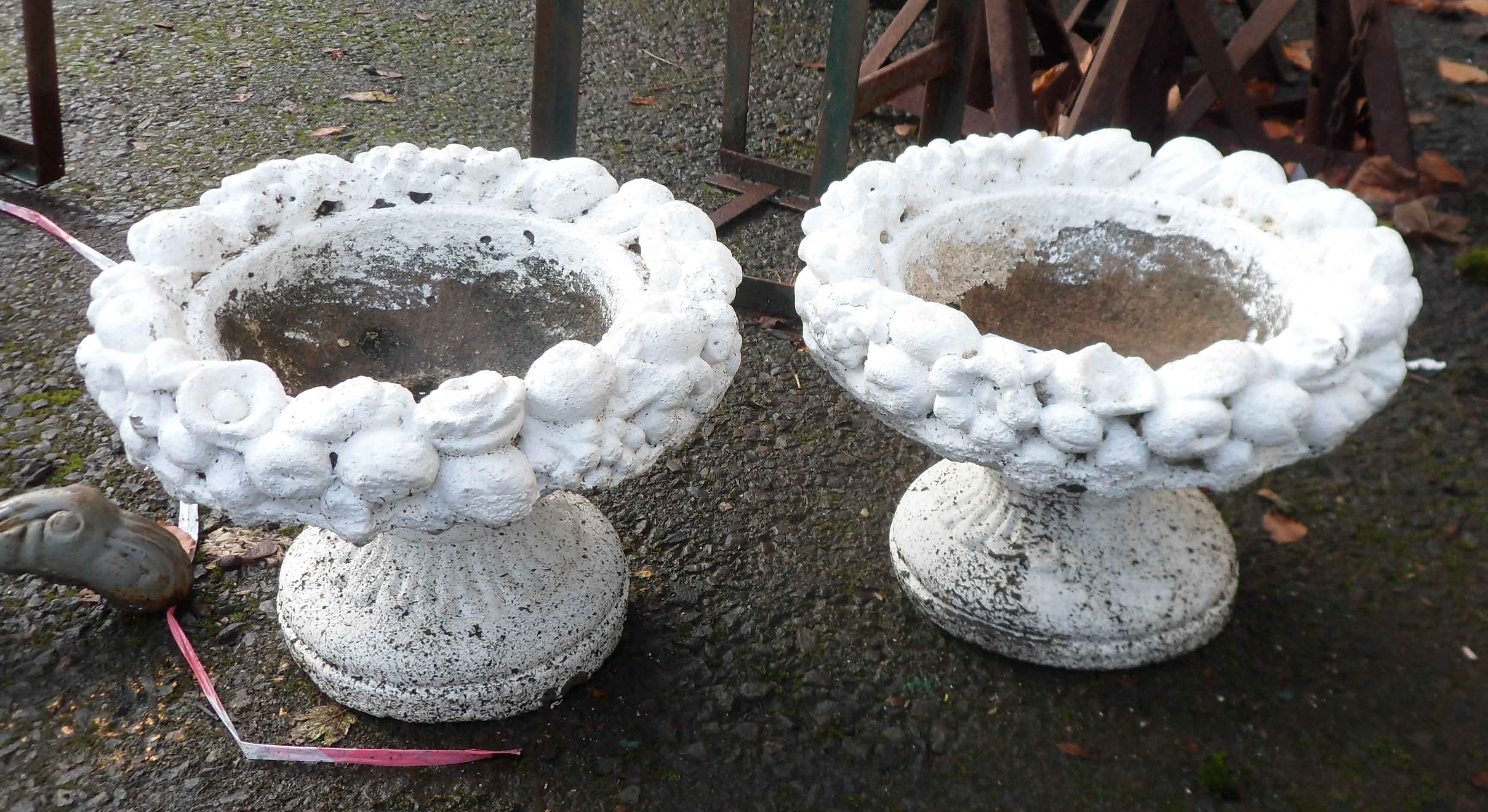 A pair of small concrete planters with floral decoration