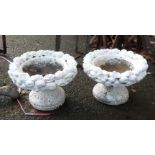 A pair of small concrete planters with floral decoration