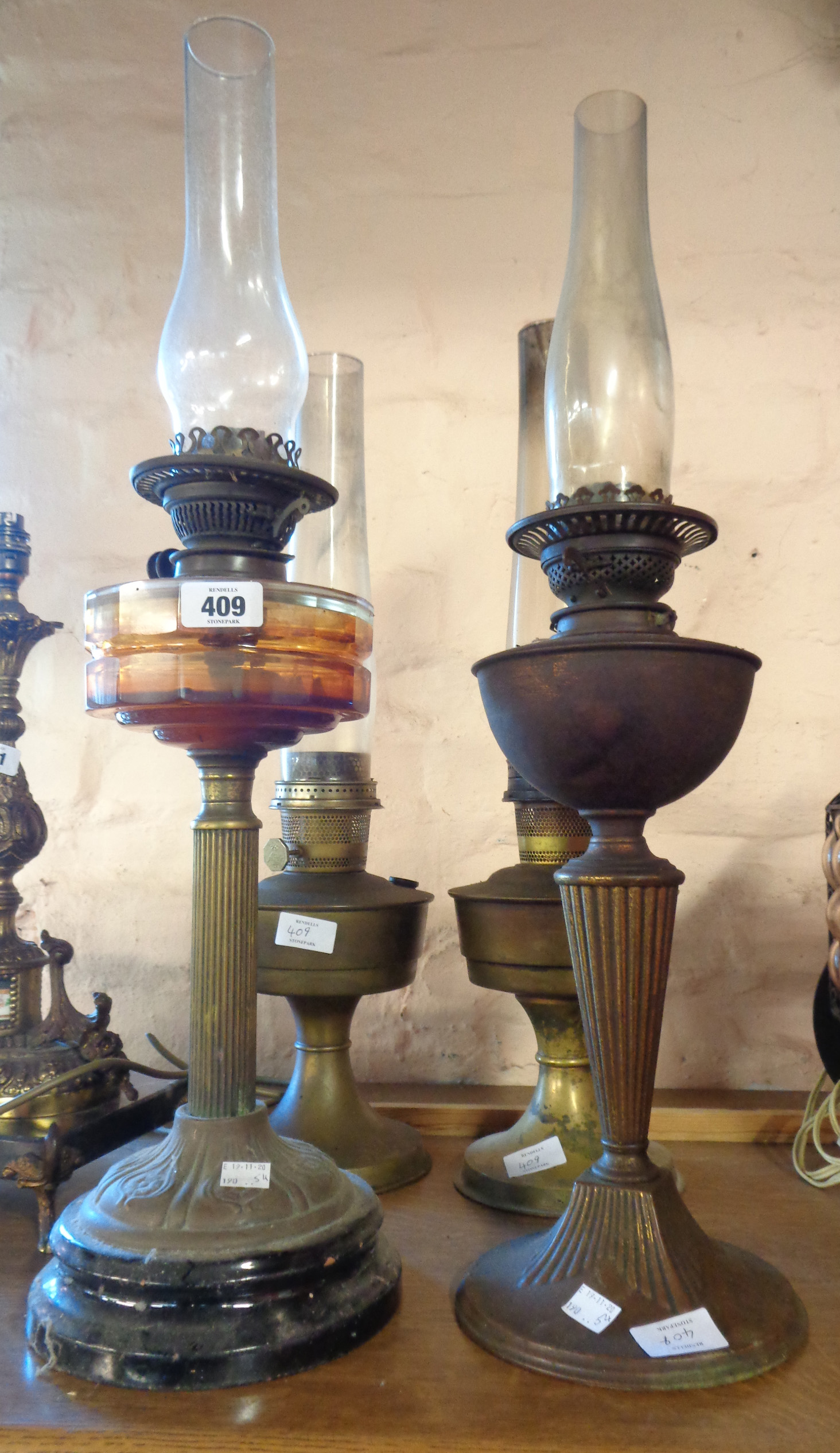 A brass Corinthian column table oil lamp with faceted glass reservoir - sold with a similar brass