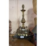 An ormolu lamp with inset porcelain panel and set on a black marble base and ormolu feet