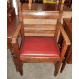 An Arts & Crafts movement Gothic heavy oak framed elbow chair with chamfered decoration, leatherette