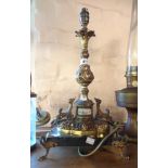 An ormolu lamp with inset porcelain panel and set on a black marble base and ormolu feet