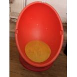 A modern child's egg chair with plastic back and metal loaded swivel base