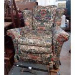 A vintage cottage wingback armchair with original upholstery and later vase and flowers fitted cover