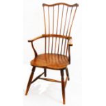 An antique pine stick back Windsor elbow chair with moulded solid elm seat, set on turned supports