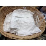 A wicker basket containing assorted linen and lace including children's Christening dresses, etc.