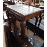 A reproduction quarter veneered figured walnut coffee table with glass inset top and two nesting tea