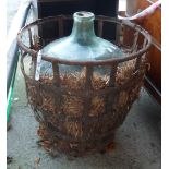 A large glass carboy with original straw filled iron cage