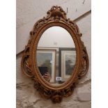 A decorative Rococo style moulded gilt plastic framed oval wall mirror