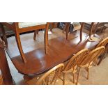 A reproduction mahogany extending dining table with single leaf, set on twin turned pedestals and