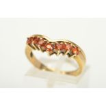 A 9CT GOLD SEVEN STONE GEM RING, designed as seven circular gems, assessed as treated orange