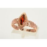 A GARNET RING, designed as a navette shaped garnet within an engraved navette shaped surround, to